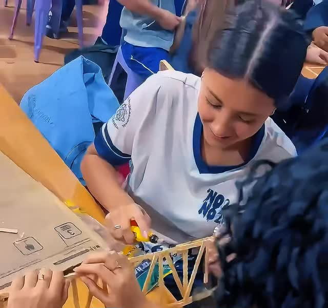 Alunas montando a estrutura de uma ponte de madeira no laboratório maker